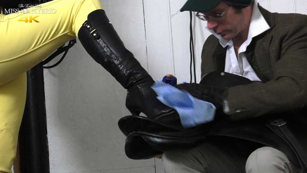 Useless groom instructed by Miss Hybrid, mistress wears her leather boots, jodhpurs and gloves as she commands her useless groom.